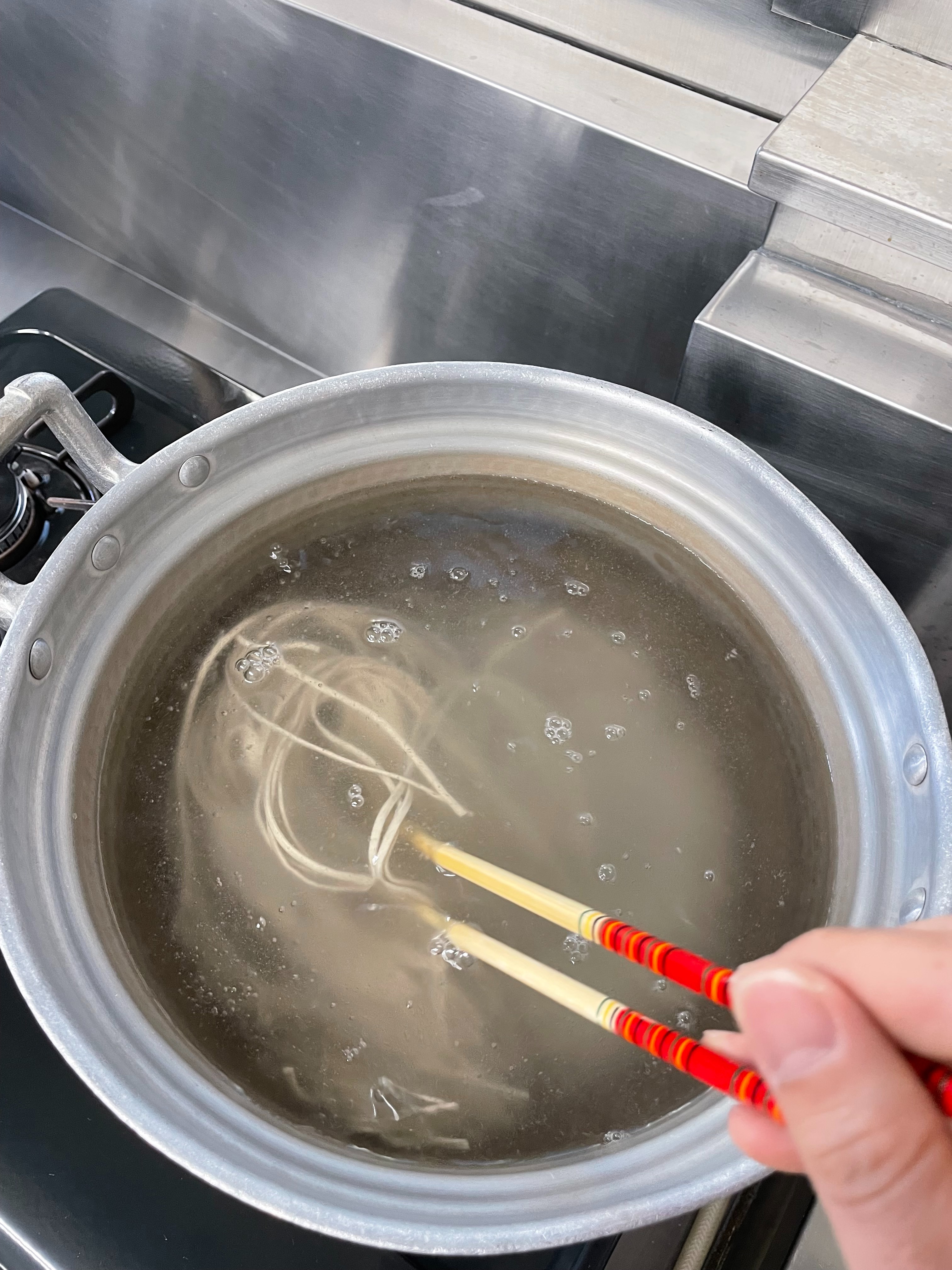 冷凍そばを箸でやさしくほぐす